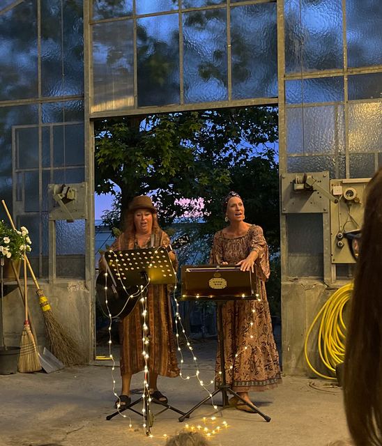 Die zwei Schrullen spielen am Abend in einem Gewächshaus mit Lichterkette