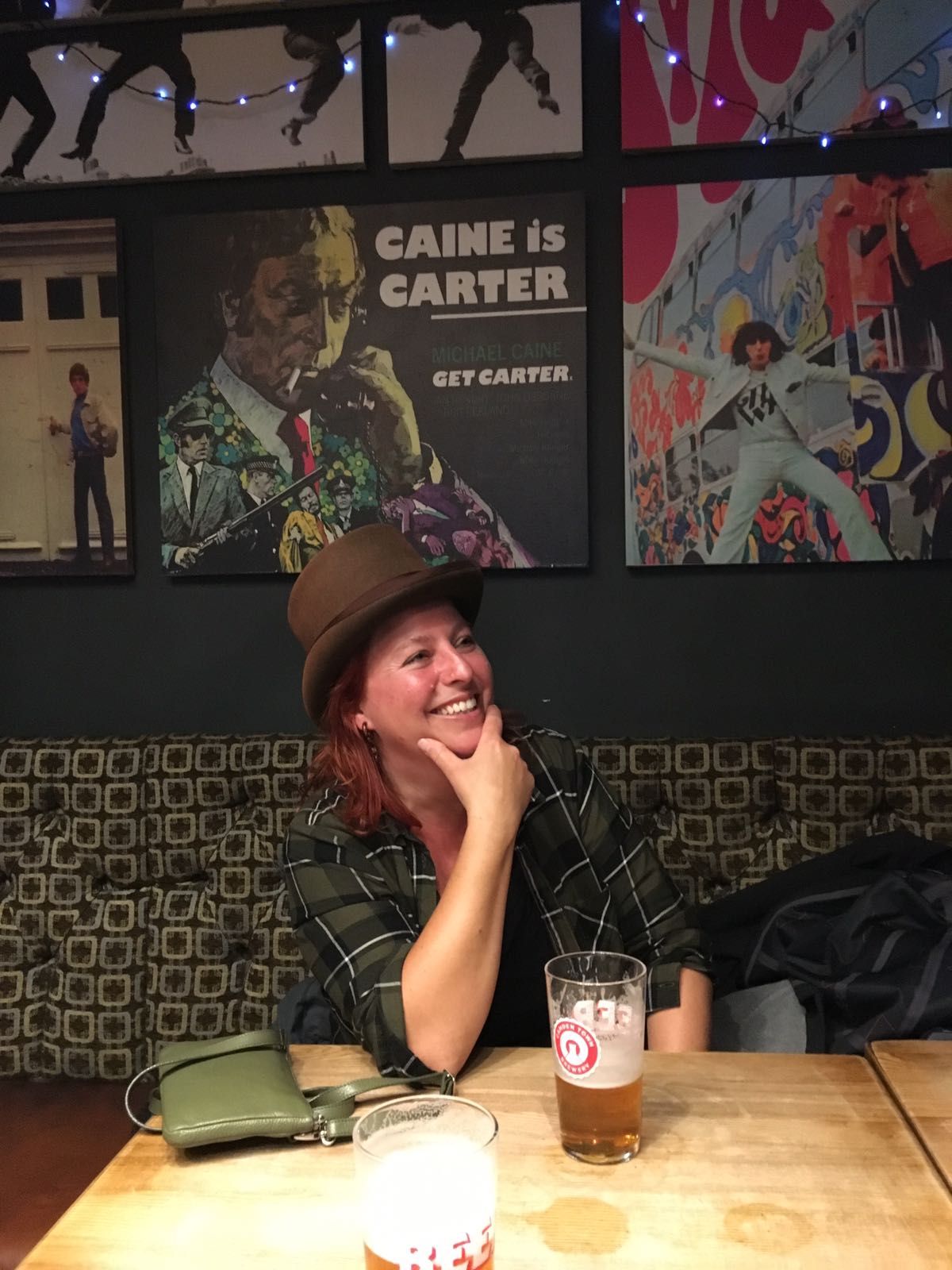 Laura Strasser mit Hut an einem Holztisch, lächelnd