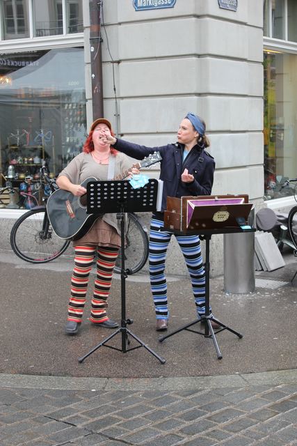 Die zwei Schrullen als Strassenmusikerinnen am Ökomarkt, mit Gitarre und Quetschkommode