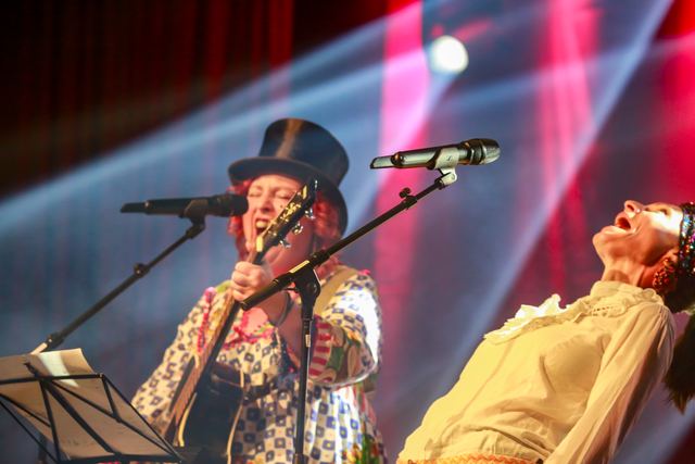 Sängerin mit Zylinder und Gitarre am Mikrofon, neben ihr lehnt die Duopartnerin theatralisch zurück