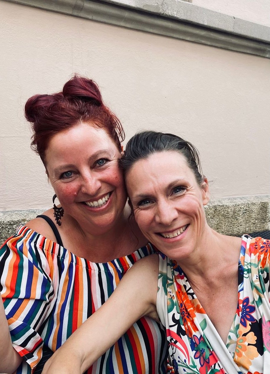 Die zwei Schrullen lachen Kopf an Kopf in die Kamera, Sommer 2025