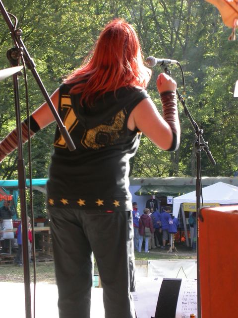 Sängerin mit roten Haaren von hinten auf einer Open-Air-Bühne, Band Spin Off