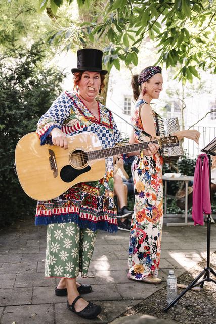 Die zwei Schrullen bei den Street Music Nights der Bandunion im Sommer 2025: eine mit Zylinder und Gitarre schneidet eine Grimasse, die andere spielt Akkordeon